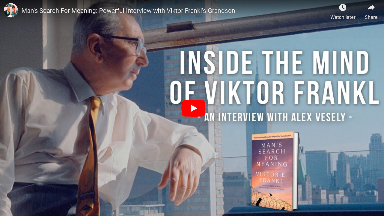 Several stories up, Viktor Frankl looks out the window with a city skyline in the distance.